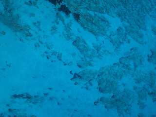 Aerial view of shallow turquoise ocean water with seafloor underneath. Overhead view of mediterran sea.