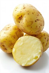 Fresh potatoes stacked on a white surface with one cut in half showing its creamy interior