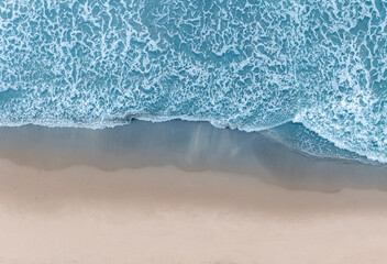 Aerial view ocean waves on remote and wild sandy beach in Italy. Background texture of water, waves and beach.