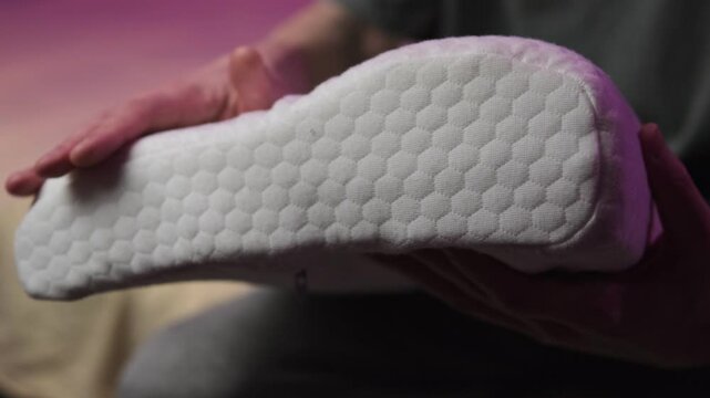 Man compresses an orthopedic pillow, the pillow takes its former shape. Memory foam