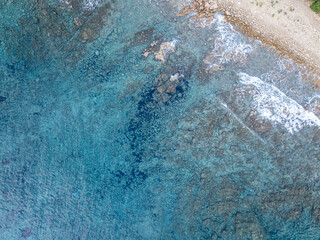 Aerial view of mediterran seafloor and coastline with waves and spray in Italy.
