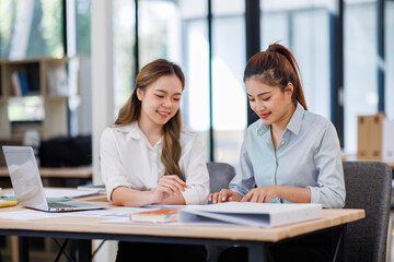 Asian Business women using calculator and laptop for doing math finance on an office desk, tax, report, accounting, statistics, and analytical research concept
