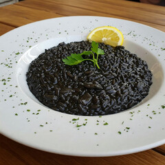 A high-quality photograph capturing the essence of black risotto, a Croatian culinary masterpiece
