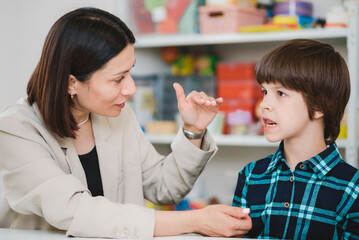A cute boy with a speech therapist is taught to pronounce the letters, words and sounds.