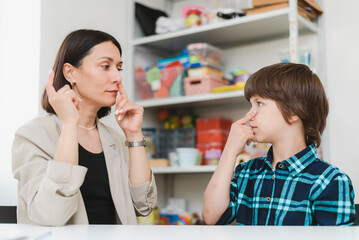 Woman speech therapist helps a boy correct the violation of his speech