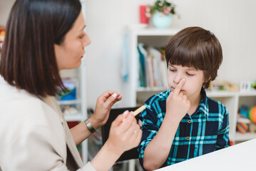 A cute boy with a speech therapist is taught to pronounce the letters, words and sounds.