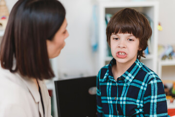 Woman speech therapist helps a boy correct the violation of his speech