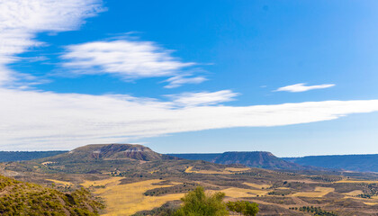 Landscape of eroded limestone hills. Yellow grass and scrub are distributed throughout the area