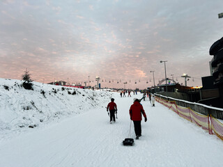 Winter scene with skiers walking under a vibrant sunset on snowy terrain