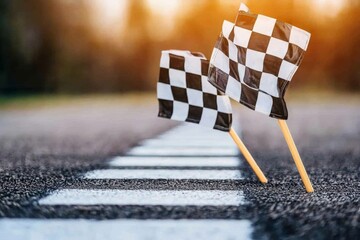 Finish line marked with checkered flags on a racetrack during sunset with a soft blurred background