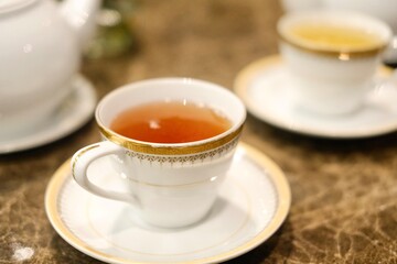 Fine bone china teacups with gold trim and two pots of tea: Taiwanese tie guan yin oolong and Japanese sencha, at the lounge of Montien Surawong, a hotel in Silom - Bang Rak, Bangkok, Thailand