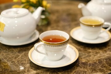 Fine bone china teacups with gold trim and two pots of tea: Taiwanese tie guan yin oolong and Japanese sencha, at the lounge of Montien Surawong, a hotel in Silom - Bang Rak, Bangkok, Thailand