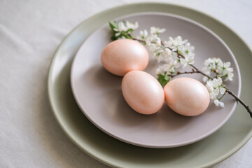 Easter table setting with peach Easter eggs and cherry blossom branch on grey plate