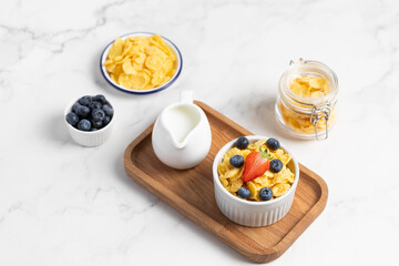 cornflakes with blueberries in a bowl and milk on a light background, breakfast