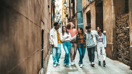 Happy multiracial group of friends walking on city street - Cheerful young people hanging outside together - Friendship concept with guys and girls having fun outdoors