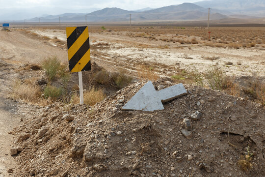 A weathered road sign and a direction marker guide travelers along the Gorgan Bojnord road in Iran, surrounded by arid landscape and mountains.