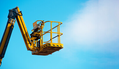 Elevated mobile platform cherrypicker used for construction work under a clear blue sky
