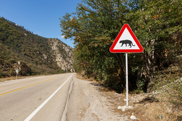 A warning sign alerts drivers to wildlife crossing on the Gorgan Bojnord road surrounded by lush greenery in Golestan National Park.