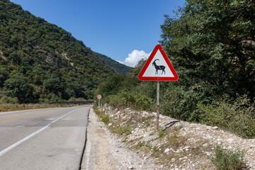 A wildlife warning sign stands near the Gorgan Bojnord road in Golestan National Park, indicating potential animal crossings in the area.