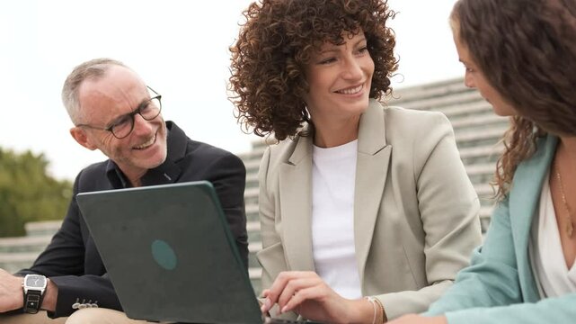 Happy businesspeople using netbook sitting on steps