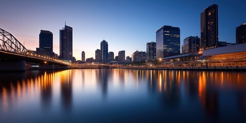 Fototapeta premium A stunning cityscape at dusk, featuring illuminated skyscrapers and a suspension bridge casting reflections on calm waters, symbolising progress and connection