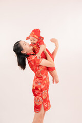 Obraz premium Chinese New Year theme, A young mother wearing Chinese traditional dress and her cute little children, in red costume with a smile on her face celebrating the Chinese festival together.