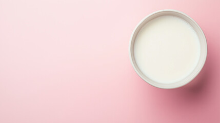  a bowl with milk on a pink background, top view