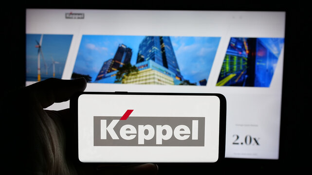 Stuttgart, Germany - 01-22-2025: Person holding cellphone with logo of Singaporean company Keppel Ltd. on screen in front of business webpage. Focus on phone display.