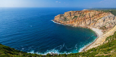 Bay, cove or inlet in Cabo Espichel Cape and a view over the Atlantic Ocean. Seascape of a natural beach surrounded by cliff. Sesimbra, Portugal