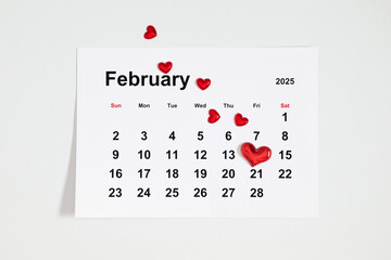 Top view of a calendar paper sheet for February 2025. The 14th is marked with a red heart on a...