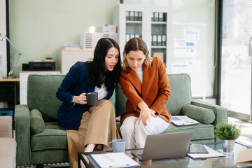 Two businesswomen collaborate using a tablet in a stylish office setting. Perfect for concepts