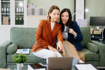 Two businesswomen collaborate using a tablet in a stylish office setting. Perfect for concepts