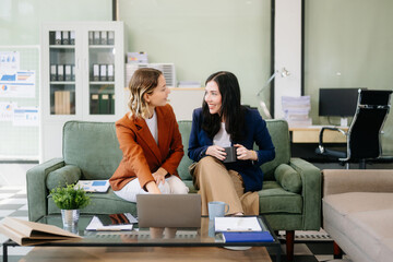 Fototapeta premium Two businesswomen strategizing with a tablet in a professional office. Highlight teamwork, leadership,