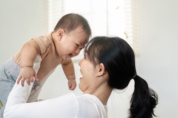 Fototapeta premium Loving mother playing joyfully with her baby during a happy moment at home