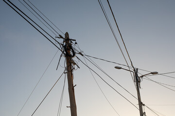 A tangled web of power lines and streetlights against a clear sky