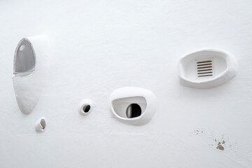 This image showcases a series of unique and unusual window designs on a white wall, highlighting...