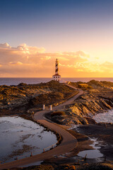 Tranquil Coastal Morning, Faro de Favaritx, Menorca. Lighthouse glowing under soft dawn light with...