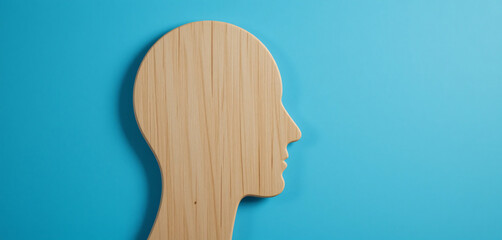 wooden human head shape cut out against a solid blue background, profile view, copy space, psychology, and mental health concept