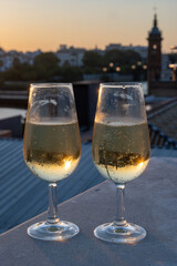 Drinking of cava or champagne sparkling wine on outdoor roof terrace with view on central part of old Sevilla, Andalusia, Spain sunset