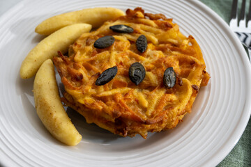 Pumpkin grated roasted patties, rosti or latkes and Fingernudel, finger potato noodle, dumplings decorated with pumpkin seeds