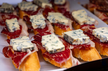 Typical snack of Basque Country, pinchos or pinxtos skewers with small pieces of bread, sea food, eggs, cheese, jamon served in bar in San-Sebastian or Bilbao, Spain, close up