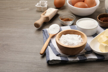 Baking powder in bowl and other products on wooden table. Space for text