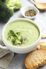 Delicious broccoli cream soup served on light table, closeup