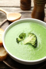 Delicious broccoli cream soup served on wooden table, closeup