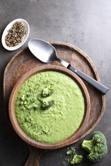 Delicious broccoli cream soup served on grey table, flat lay