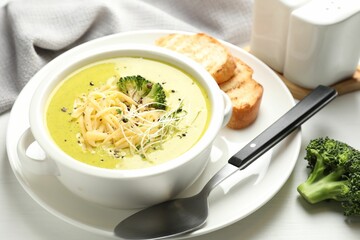 Delicious broccoli cream soup served on white wooden table, closeup