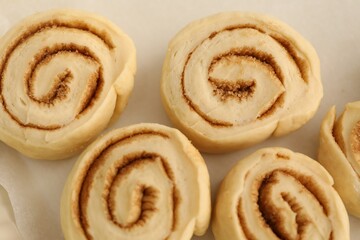 Many uncooked cinnamon rolls in baking dish, closeup