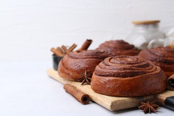 Delicious cinnamon roll buns on light table, closeup. Space for text