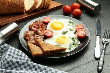 Tasty brunch. Delicious fried eggs, bacon and pieces of toast served on black table