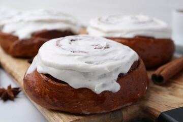 Tasty cinnamon rolls with cream on white table, closeup